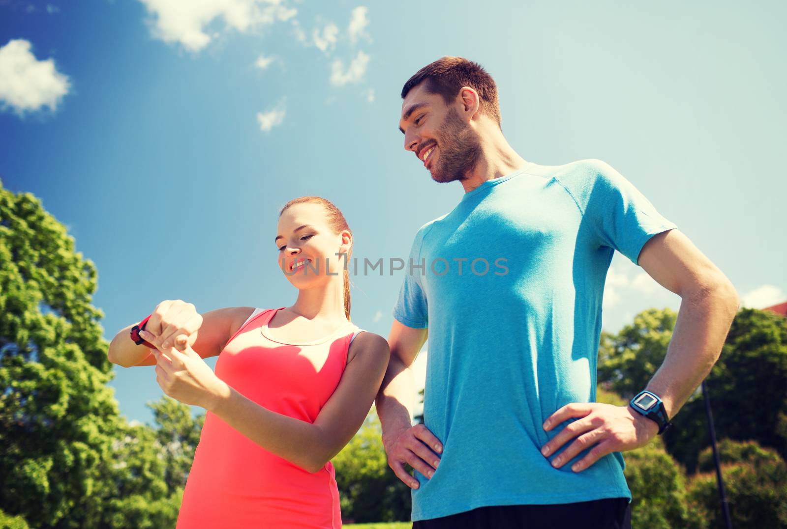 smiling people with heart rate watches outdoors by dolgachov