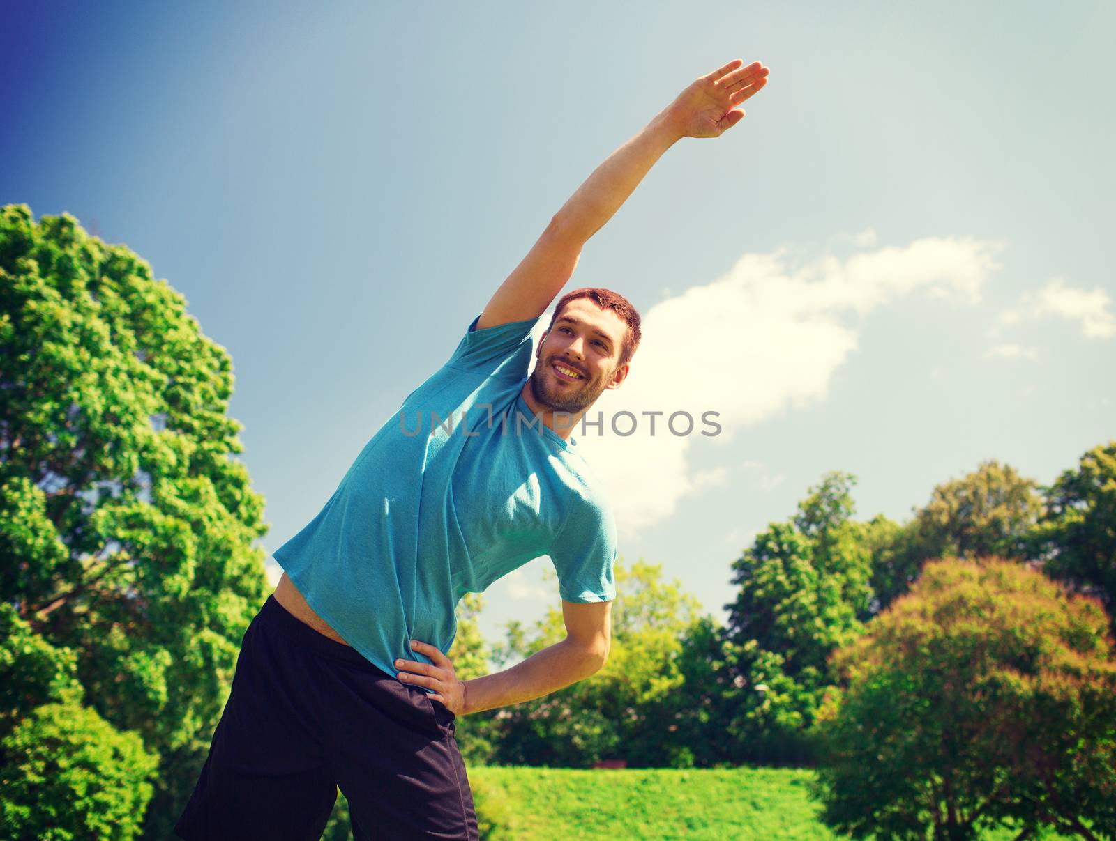 smiling man stretching outdoors by dolgachov
