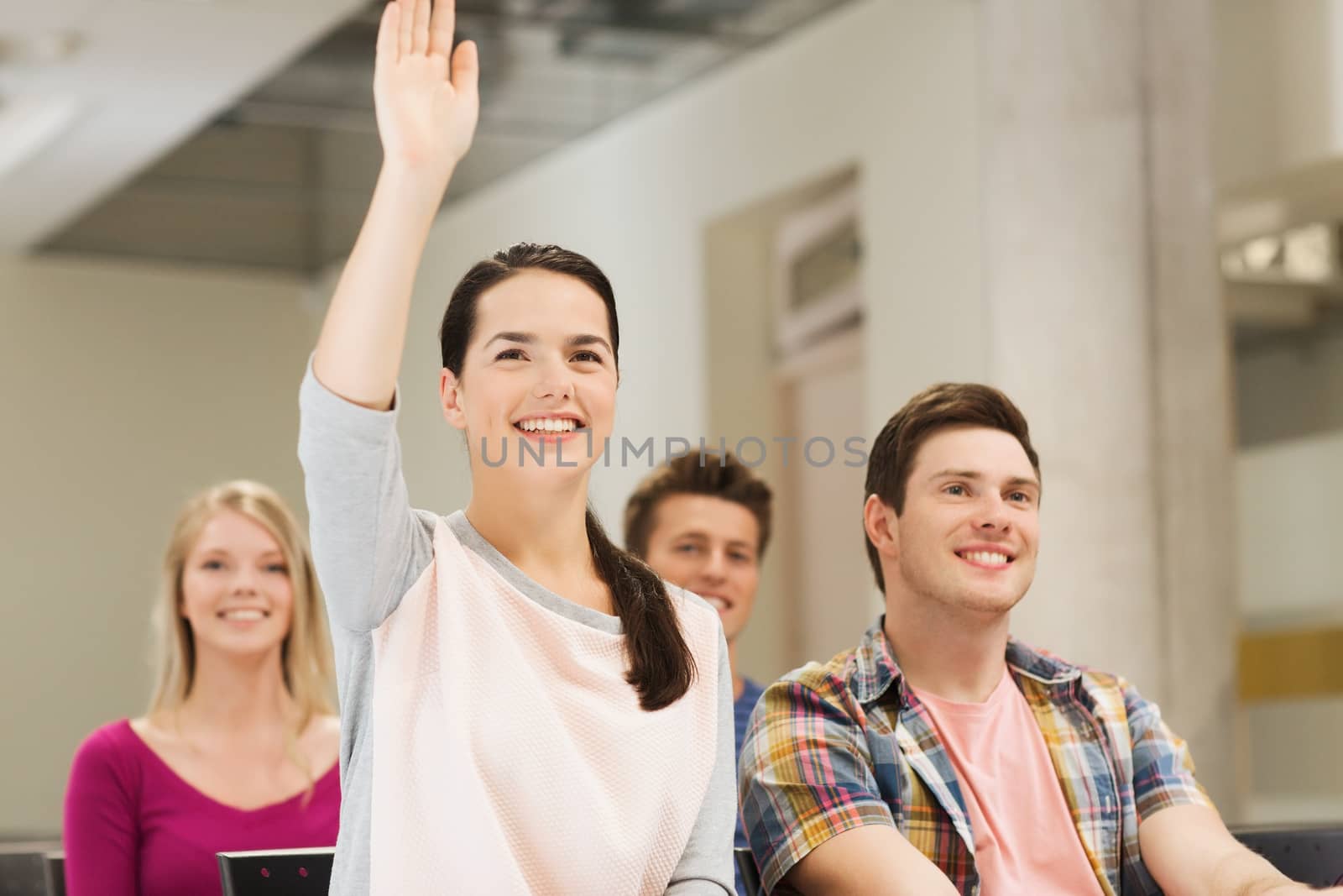 education, high school, teamwork and people concept - group of smiling students raising hand in lecture hall