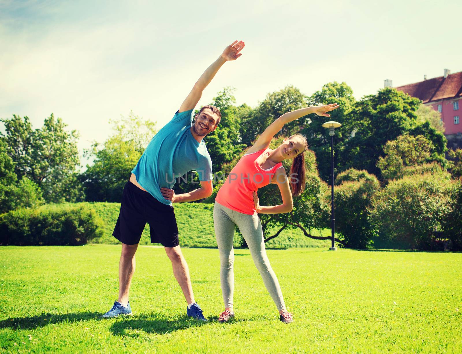 fitness, sport, training and lifestyle concept - smiling couple stretching outdoors