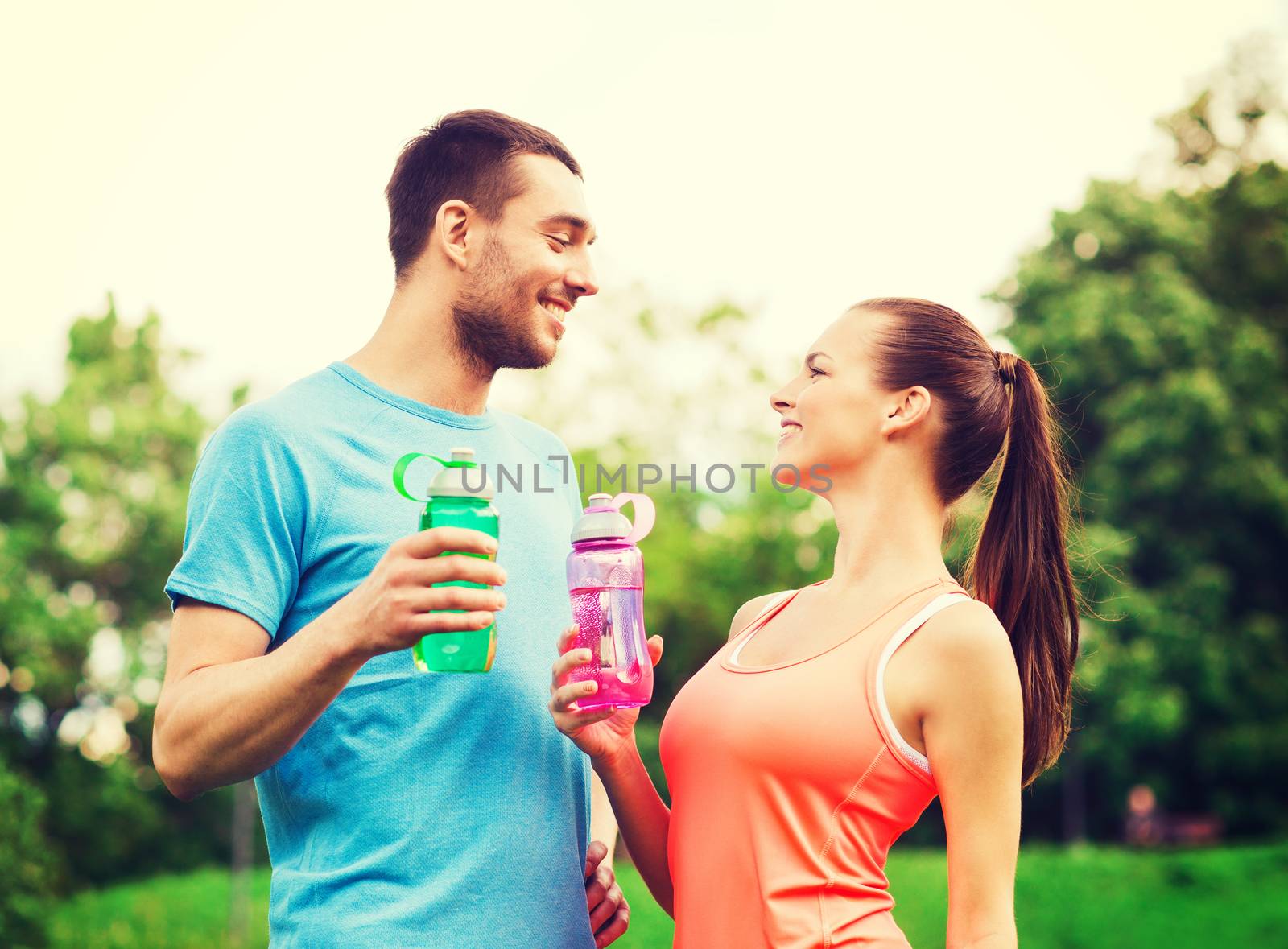 smiling couple with bottles of water outdoors by dolgachov