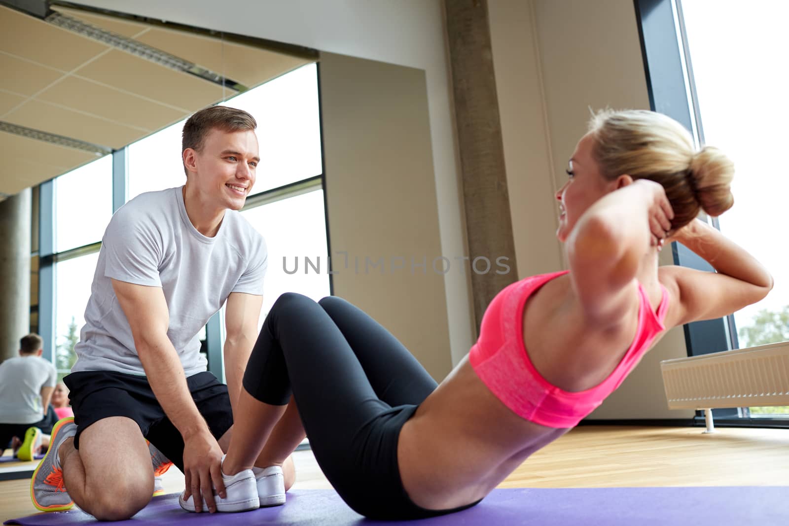 fitness, sport, training, gym and lifestyle concept - woman with personal trainer doing sit ups in gym