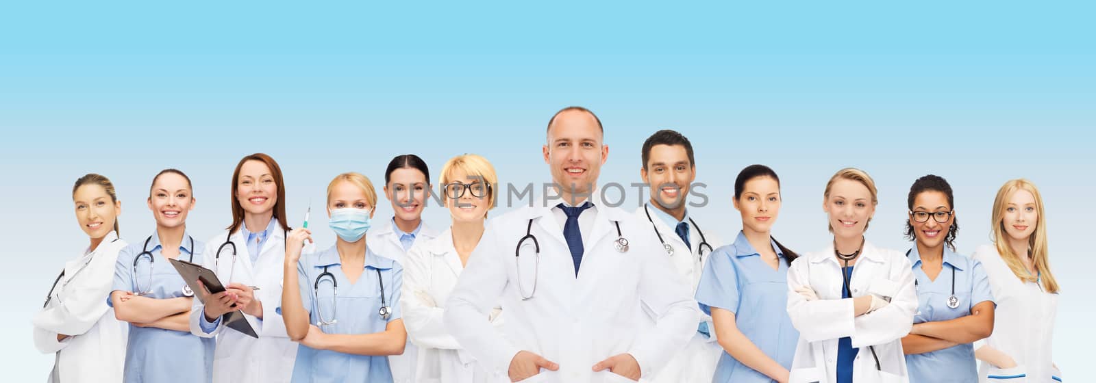 medicine, profession, teamwork and healthcare concept - international group of smiling medics or doctors with clipboard and stethoscopes over blue background