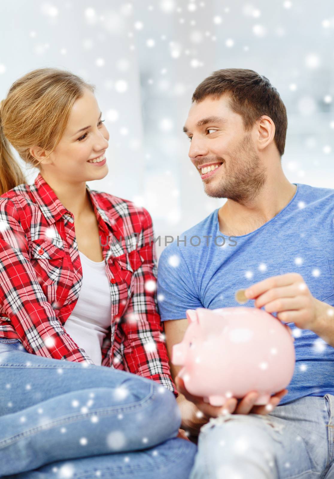 smiling couple with piggybank sitting on sofa by dolgachov