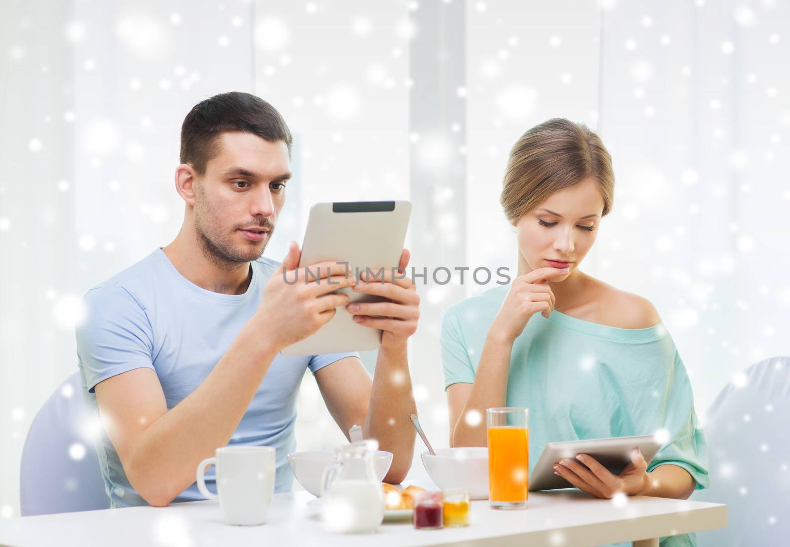 food, family, people and technology concept - couple with tablet pc computers reading news and having breakfast at home