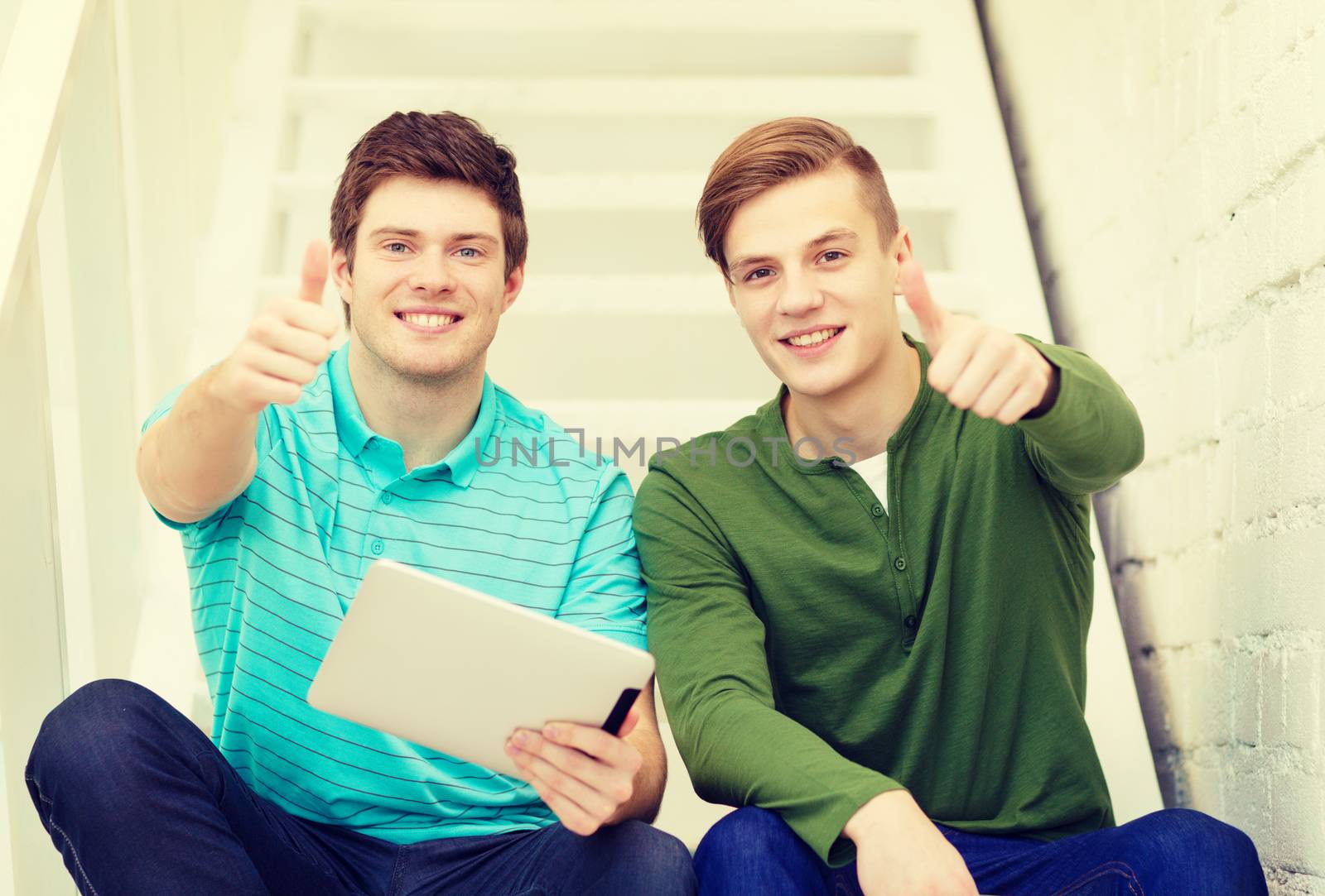 smiling male students with tablet pc computer by dolgachov