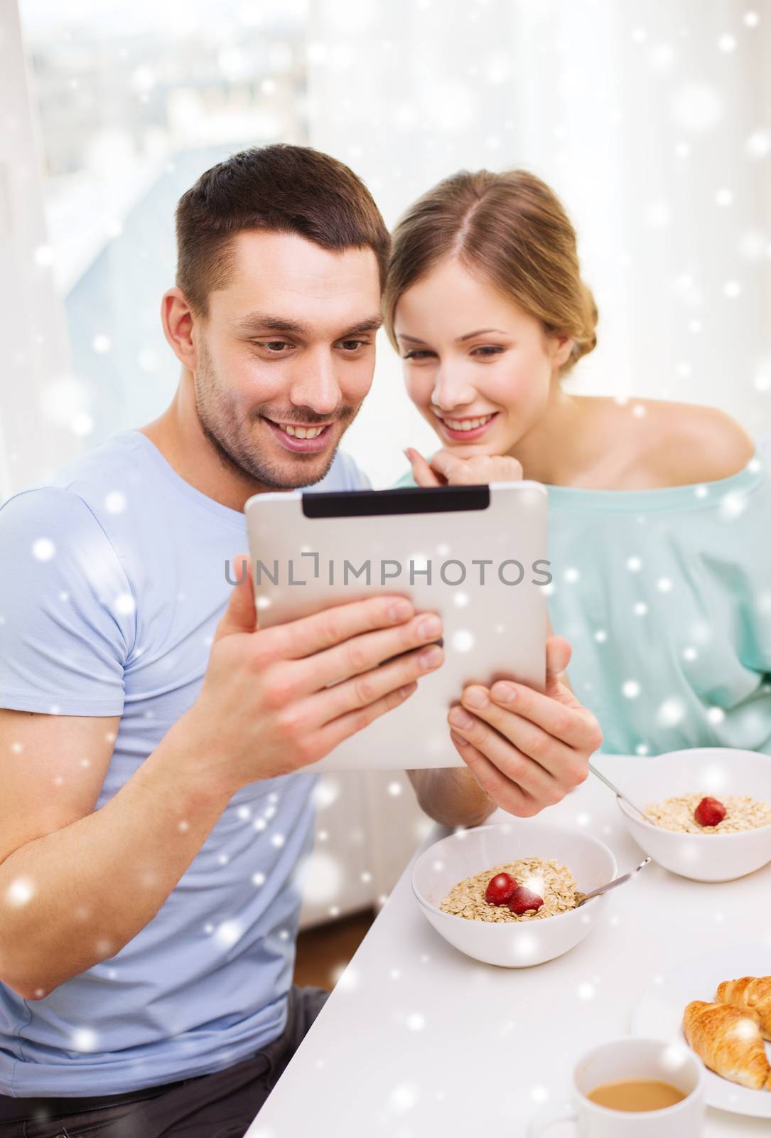 food, family, people and technology concept - smiling couple with tablet pc computer reading news and having breakfast at home