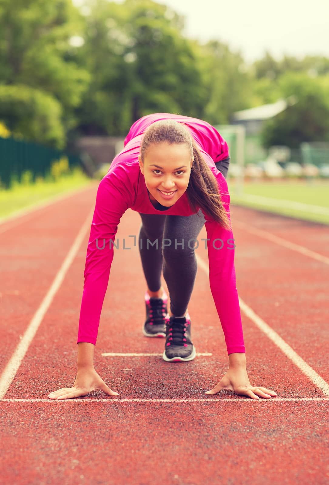 smiling young woman running on track outdoors by dolgachov