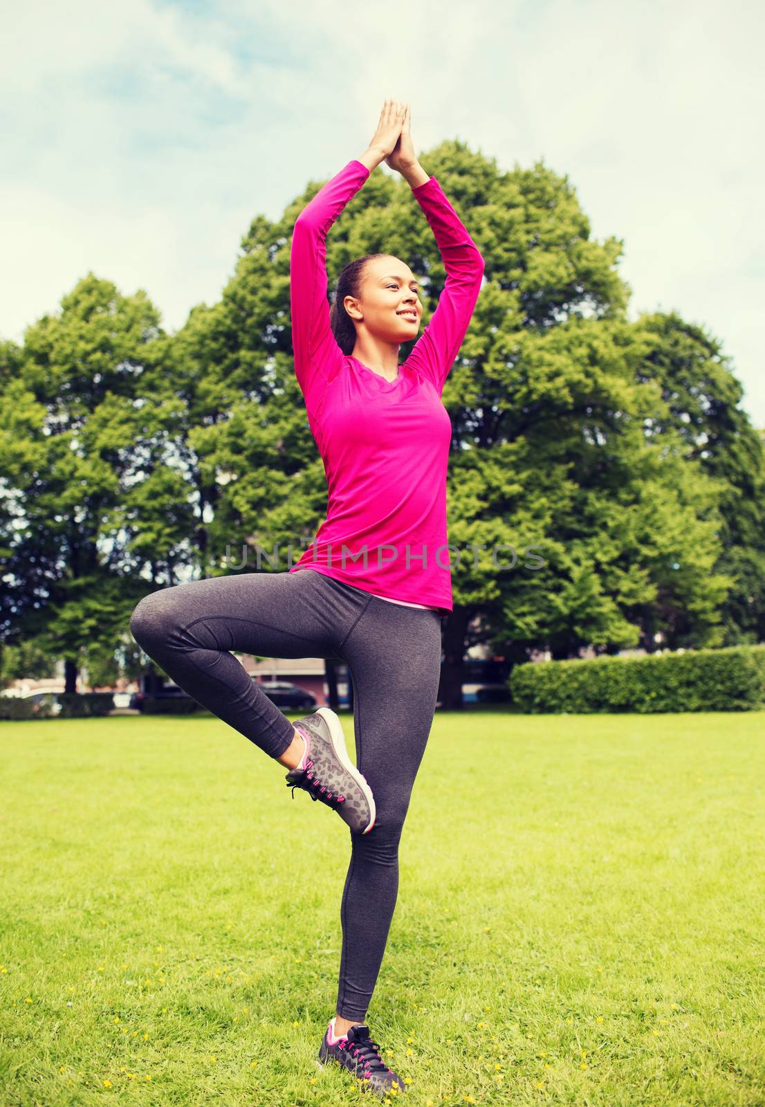 sport, exercise, yoga, park and lifestyle concept - smiling african american woman exercising outdoors