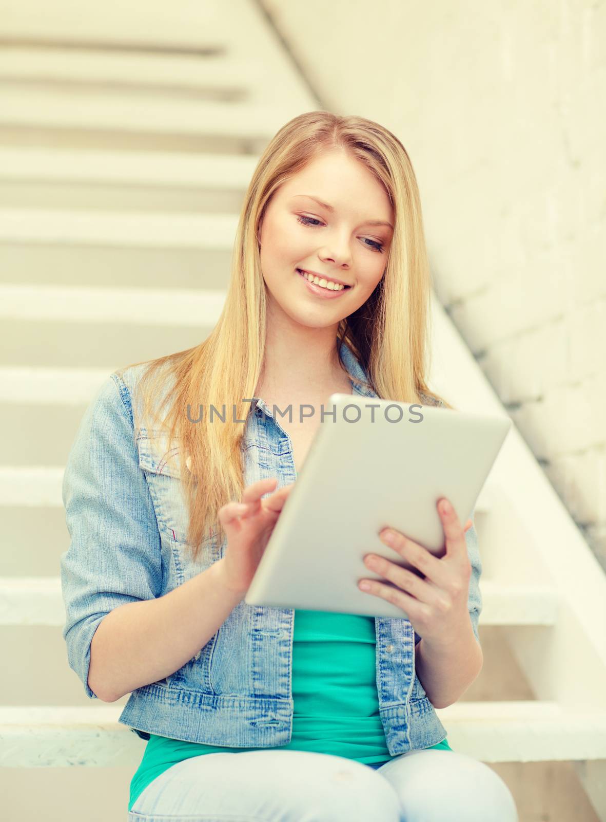 education and technology concept - smiling female student with tablet pc computer sitting on staircase