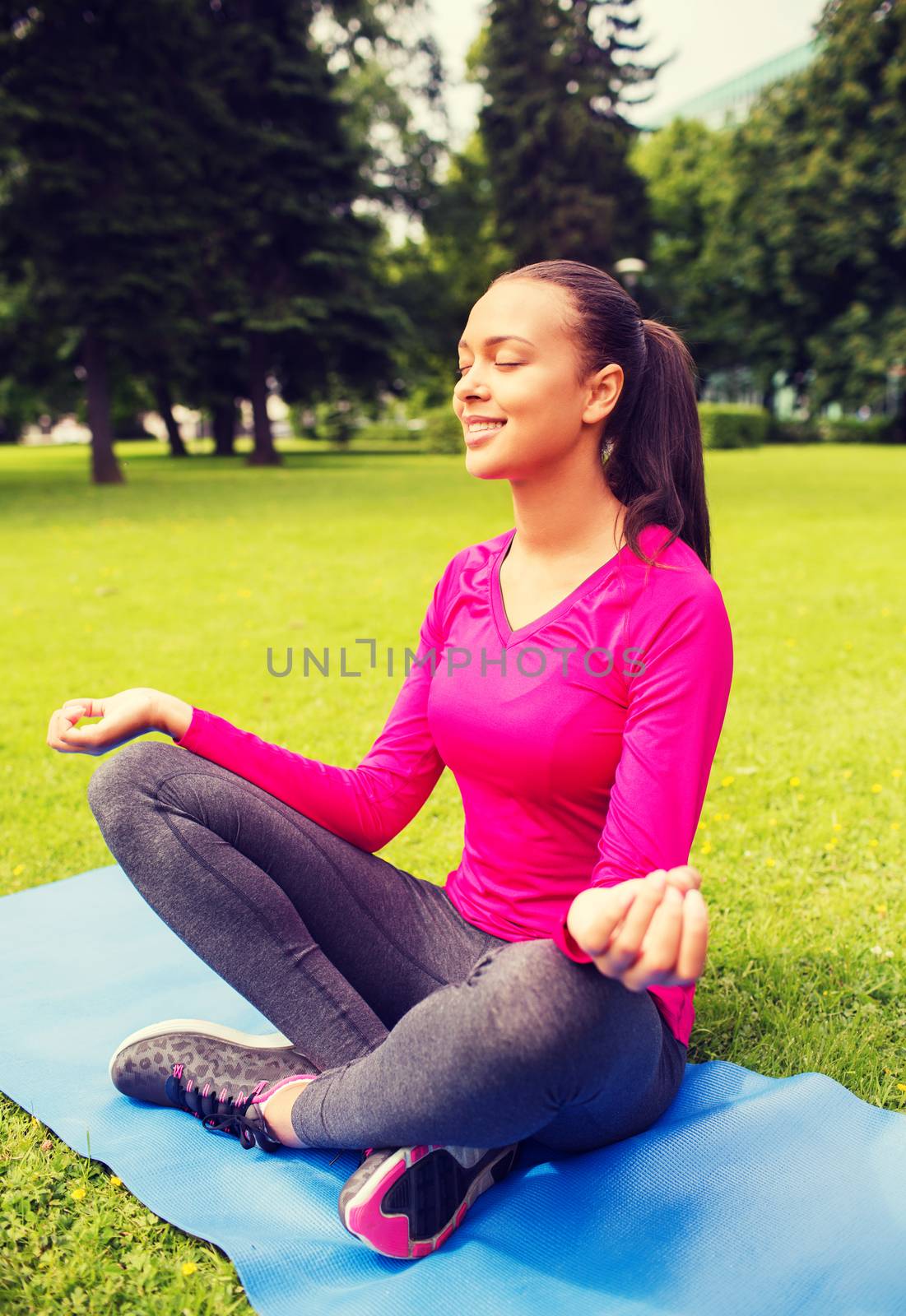 smiling woman meditating sitting on mat outdoors by dolgachov