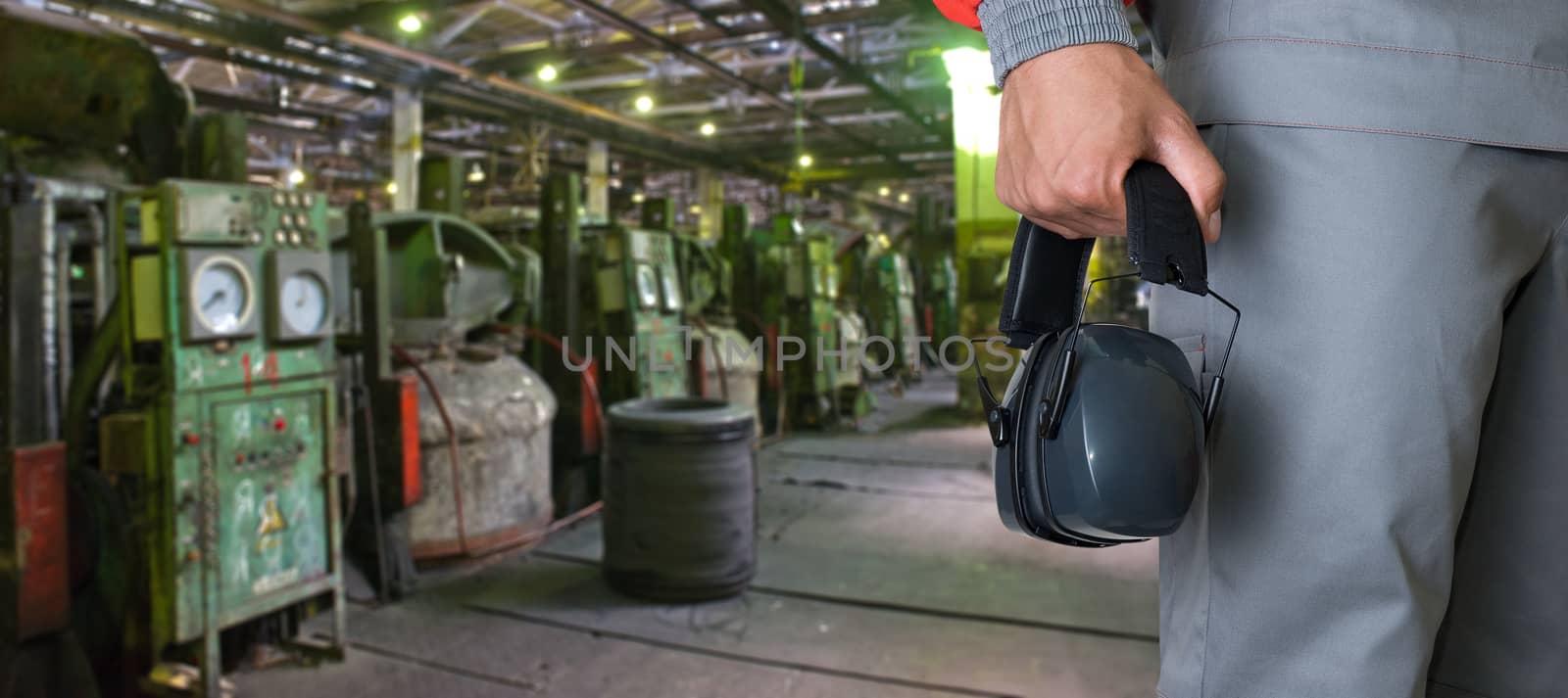 Worker with protective headphone at man hands at industrial factory