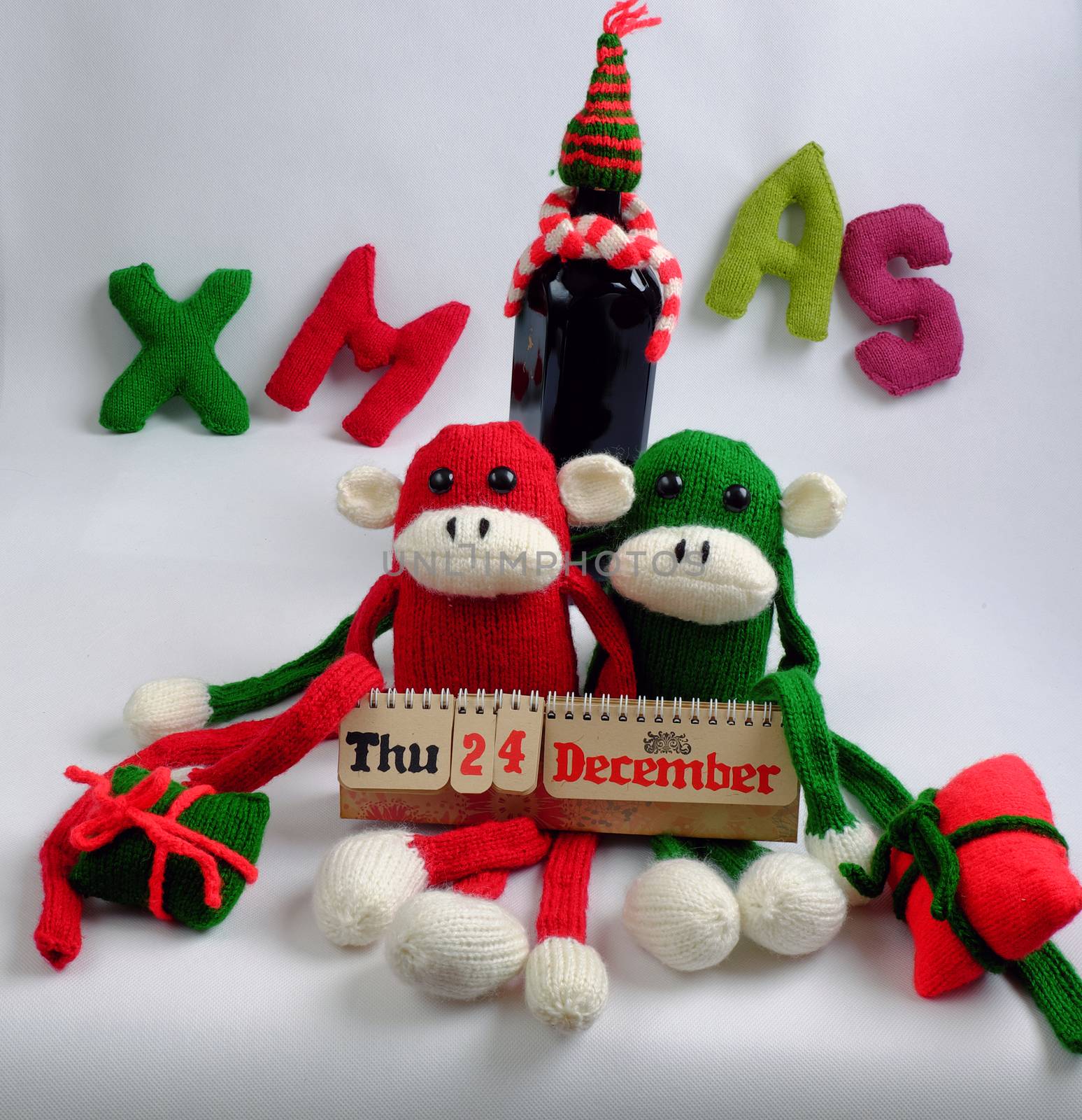 Funny Christmas background, two knitted monkey hold noel wine bottle, Xmas alphabet in red and green yarn, symbol to merry christmas and happy new year, a year of monkeys