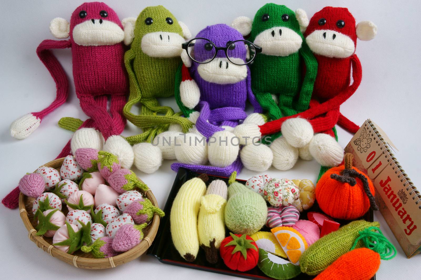 Family of stuffed animal sit at new year party, group of knitted monkey in colorful yarn, symbol of 2016, funny homemade toy on white background, handmade food and calendar to happy new year
