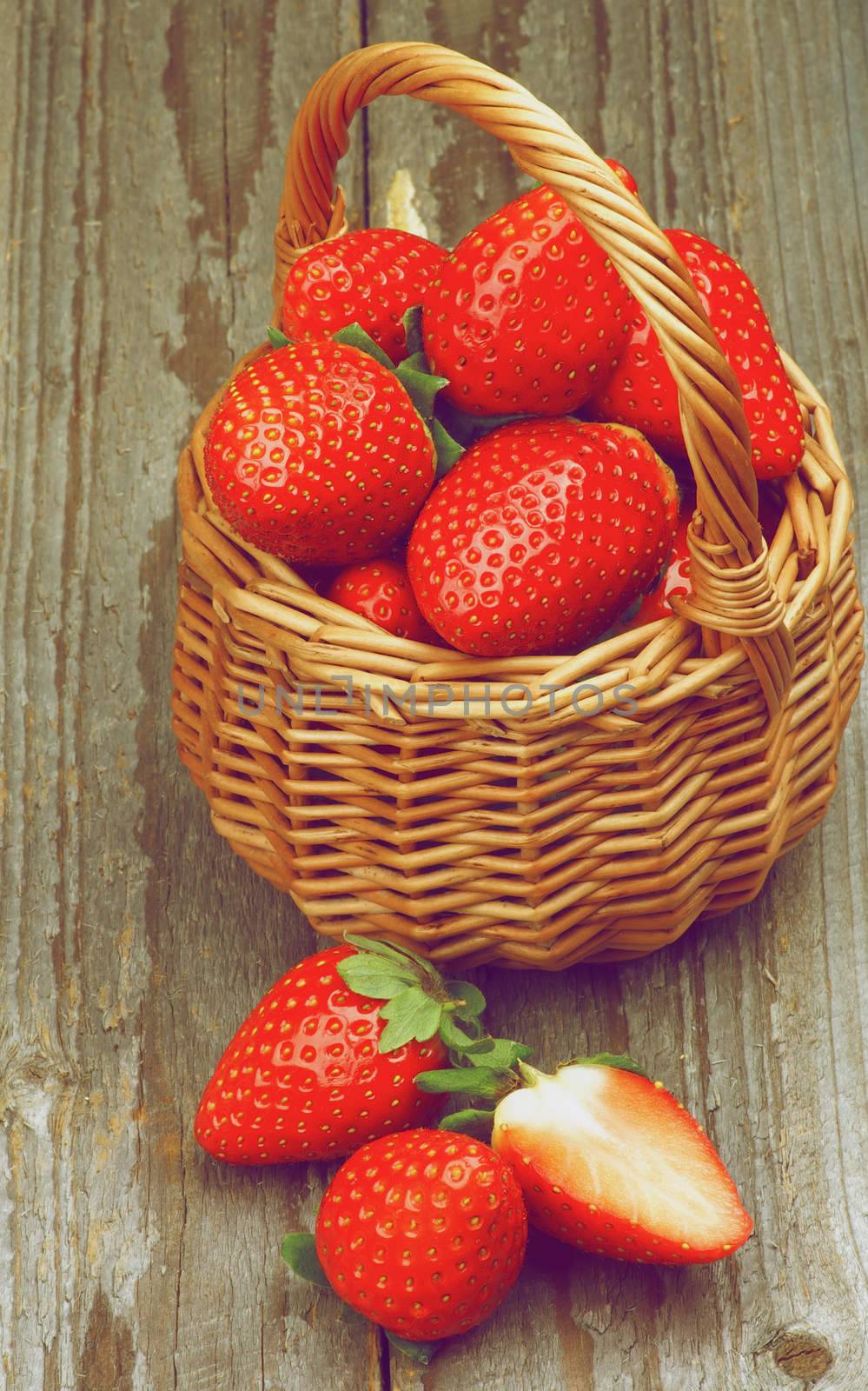 Fresh Ripe Strawberries in Wicker Basket closeup on Rustic Wooden background. Retro Styled