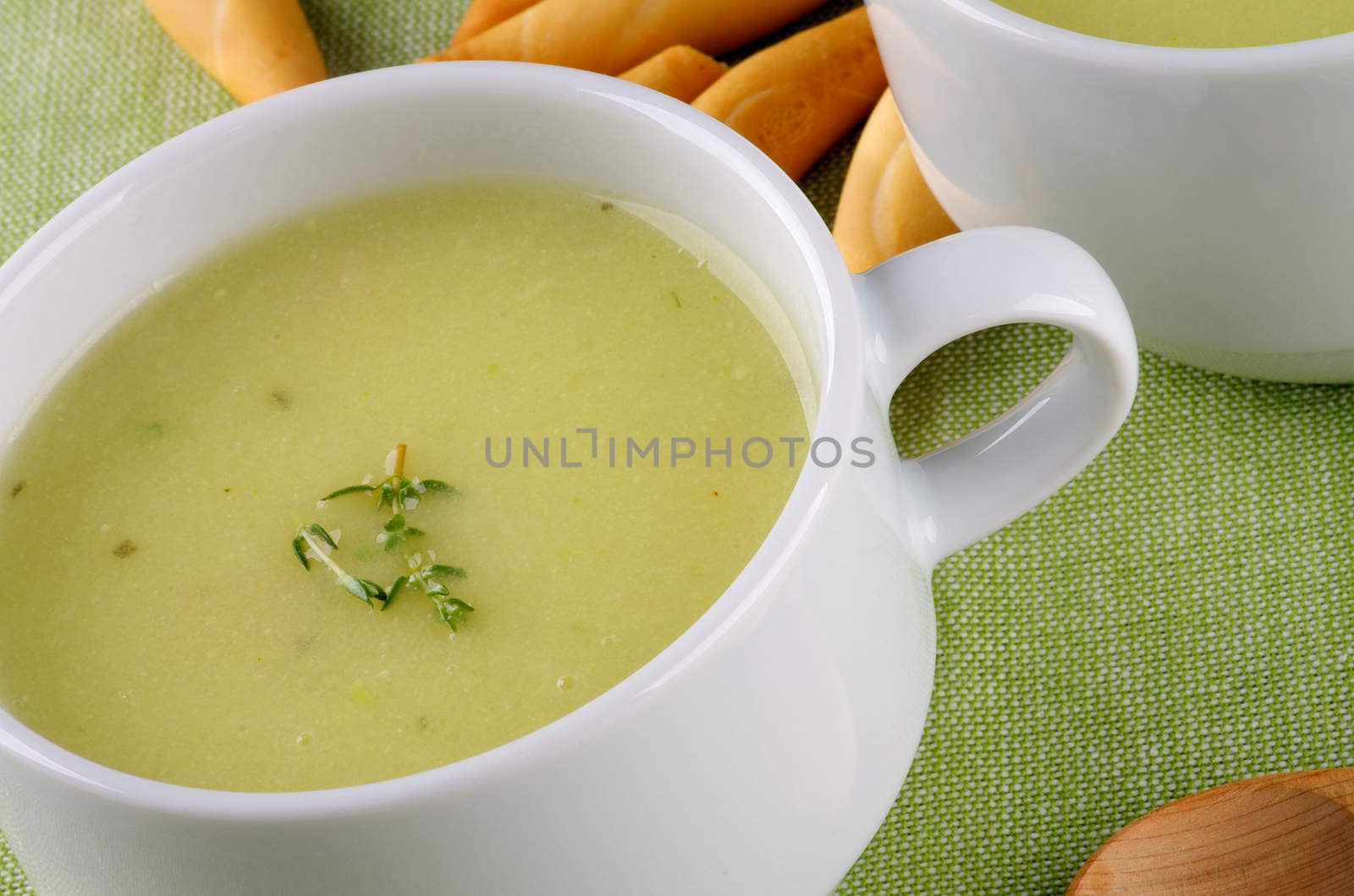 Delicious Cream Asparagus Soup in White Soup Cup with Bread Sticks Cross Section on Green Napkin