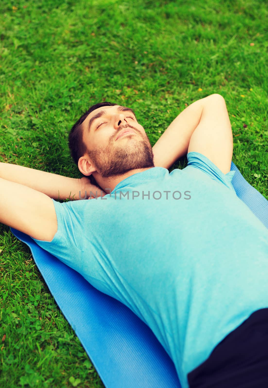 fitness, sport, training and lifestyle concept - smiling man lying on mat outdoors