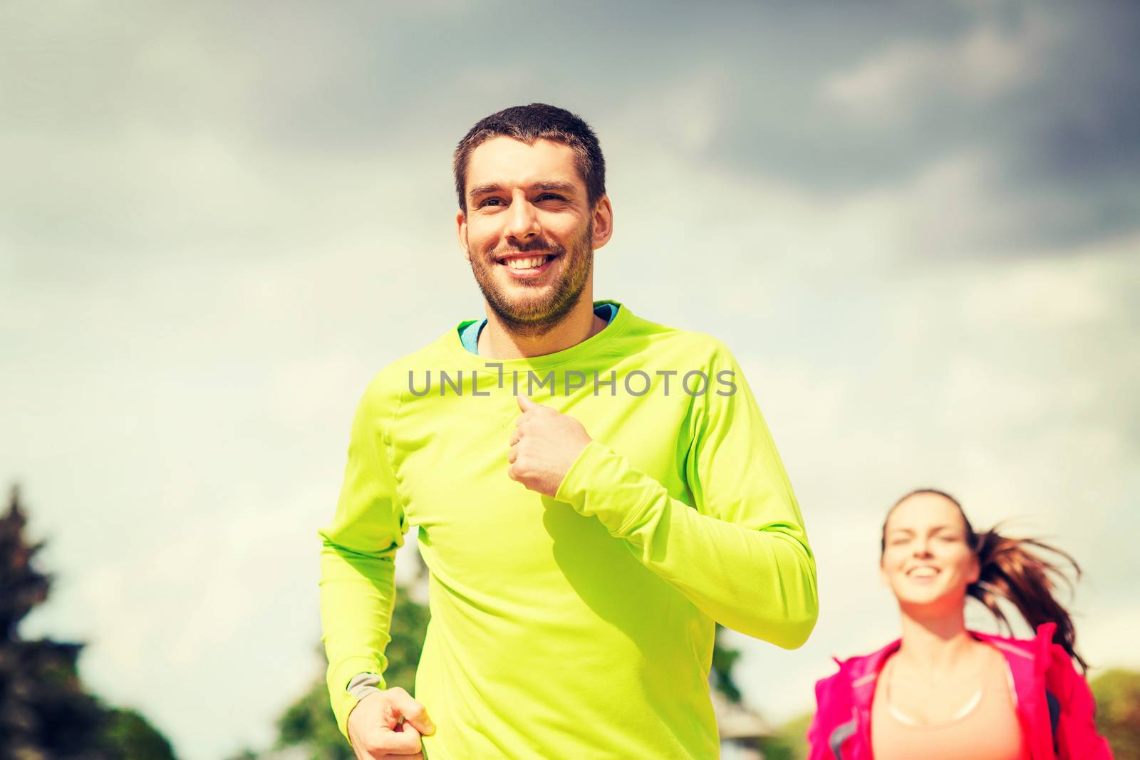 fitness, sport, friendship and lifestyle concept - smiling couple running outdoors