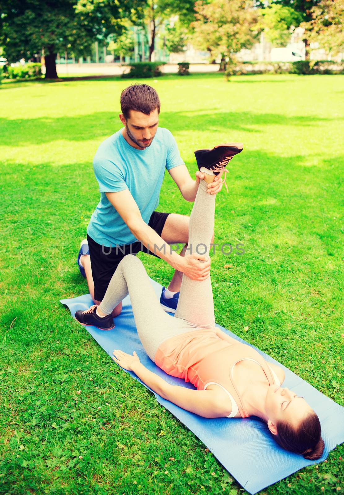 fitness, sport, training and lifestyle concept - serious couple stretching on mat outdoors
