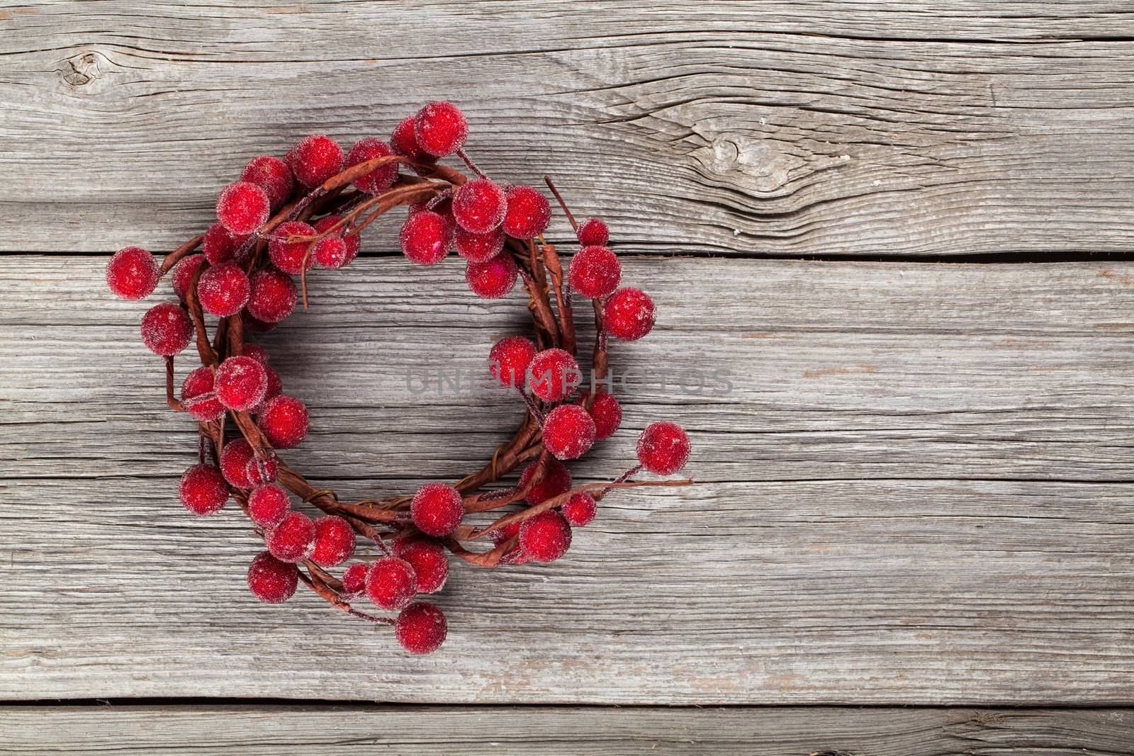 Christmas wreath from red berries on wooden background by motorolka