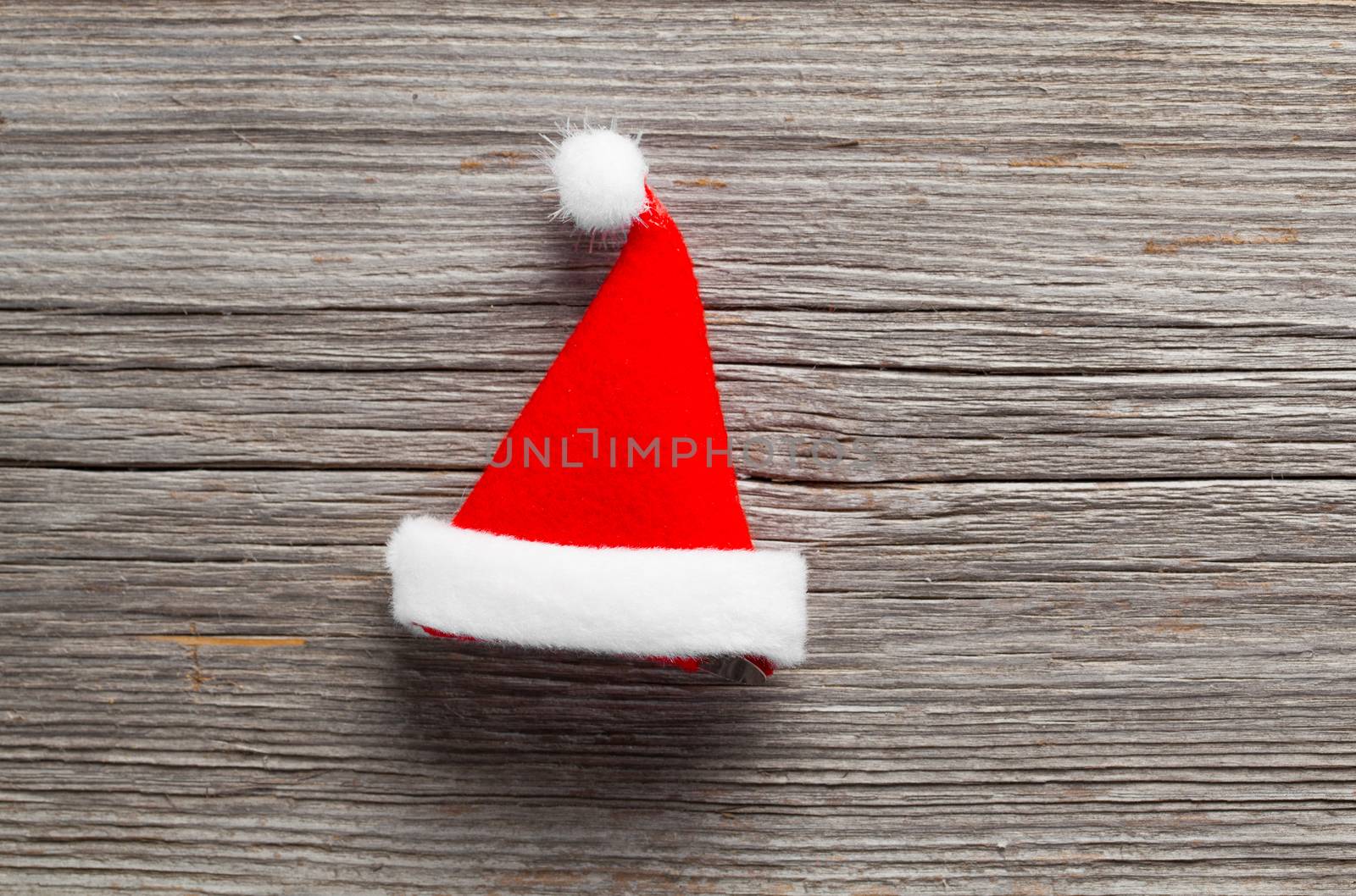 Single Santa Claus red hat on wooden background by motorolka