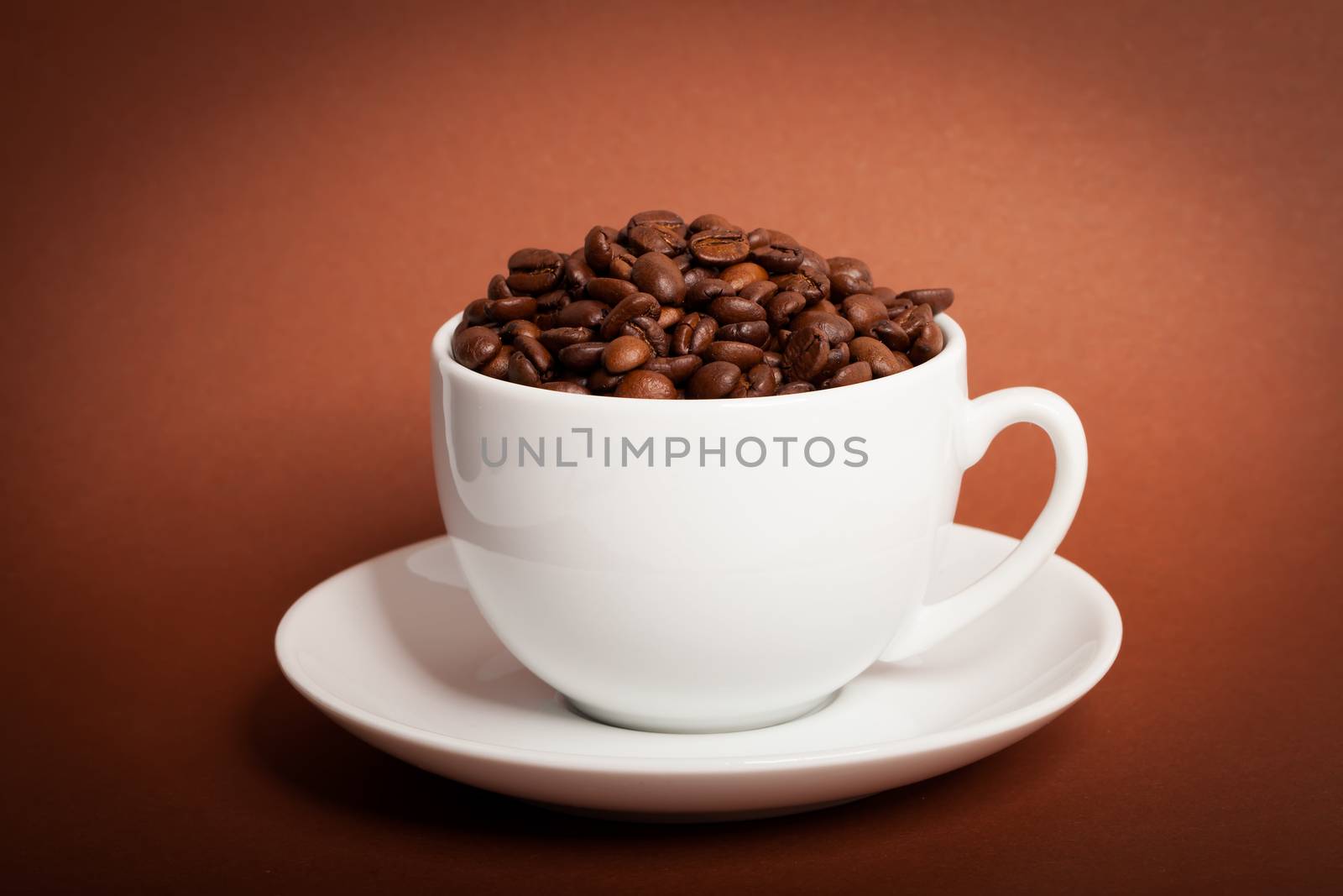 Coffee beans in cup on brown background by motorolka