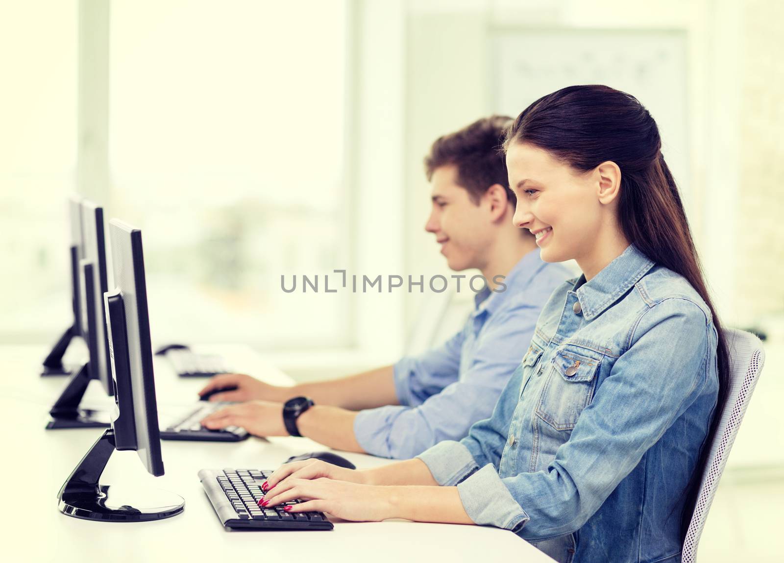 education, technology and school concept - two smiling students in computer class