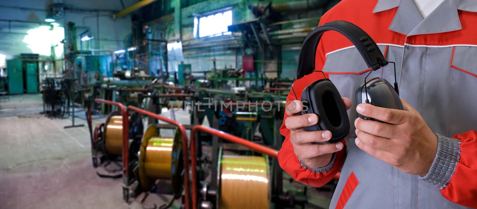 Worker with protective headphone at man hands at industrial factory