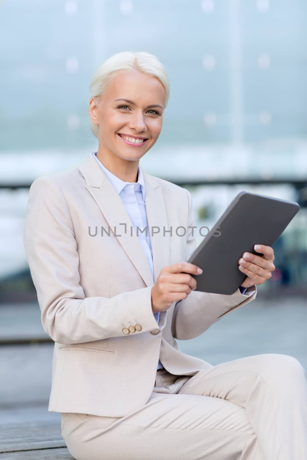 business, education, technology and people concept - smiling businesswoman working with tablet pc computer on city street
