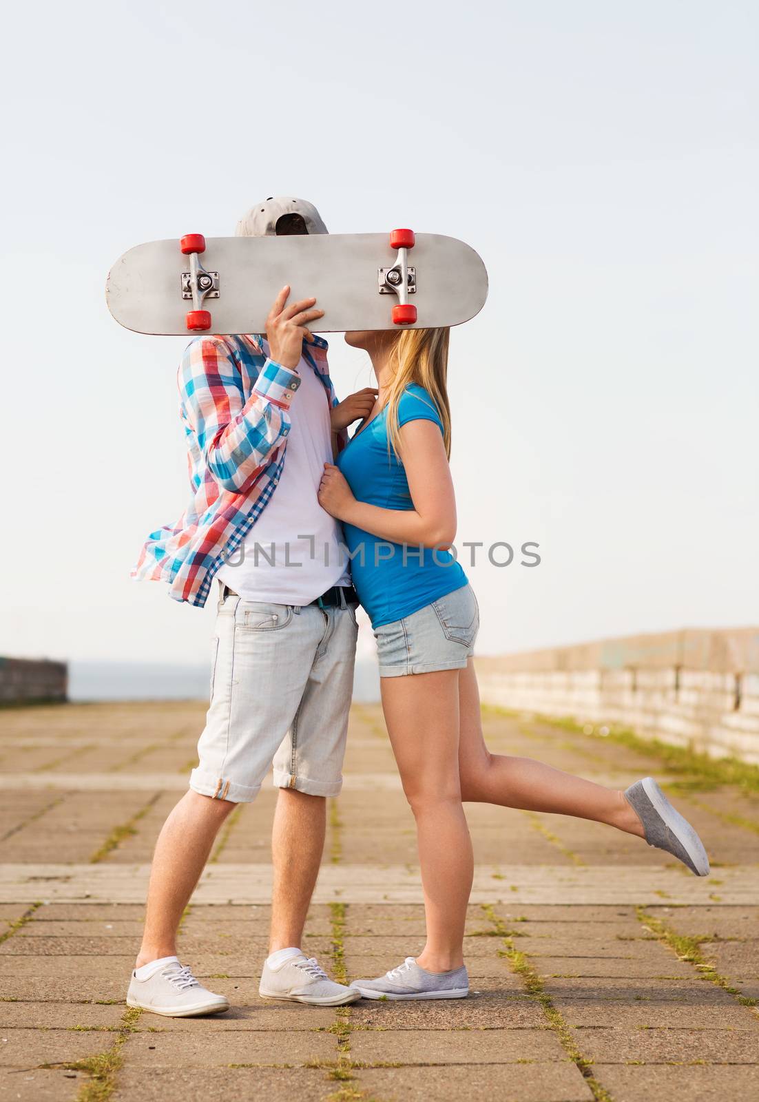 couple with skateboard kissing outdoors by dolgachov