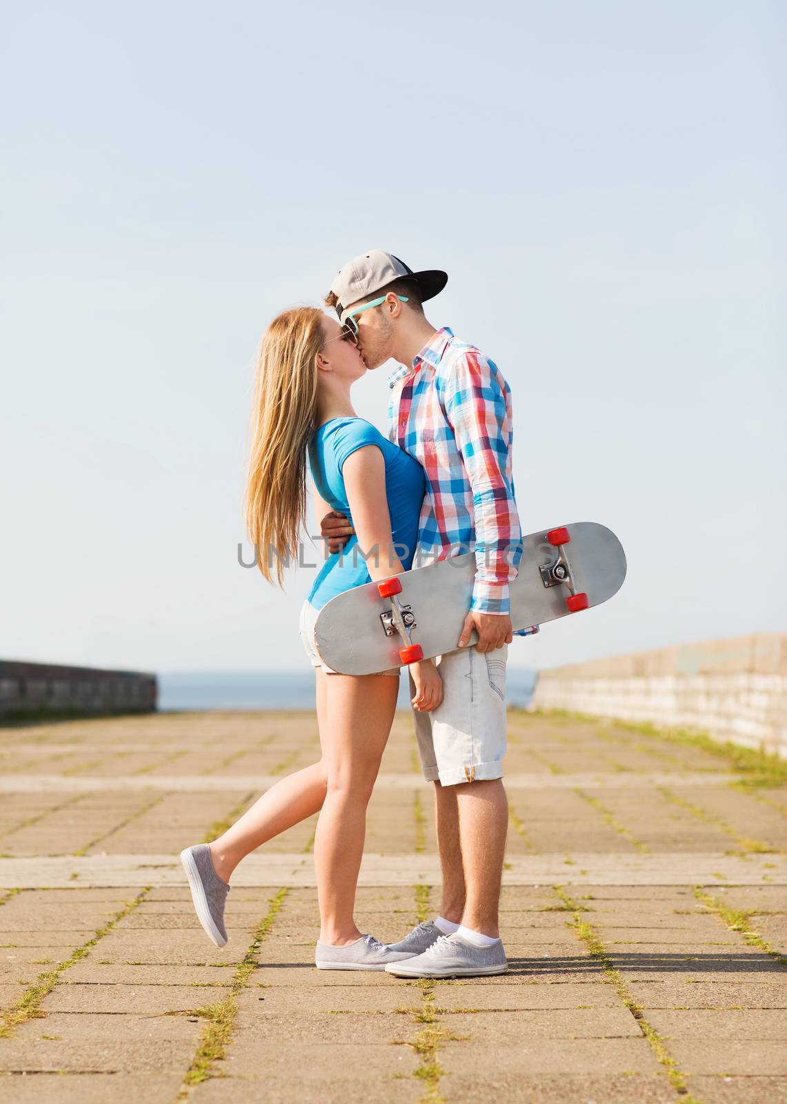 couple with skateboard kissing outdoors by dolgachov