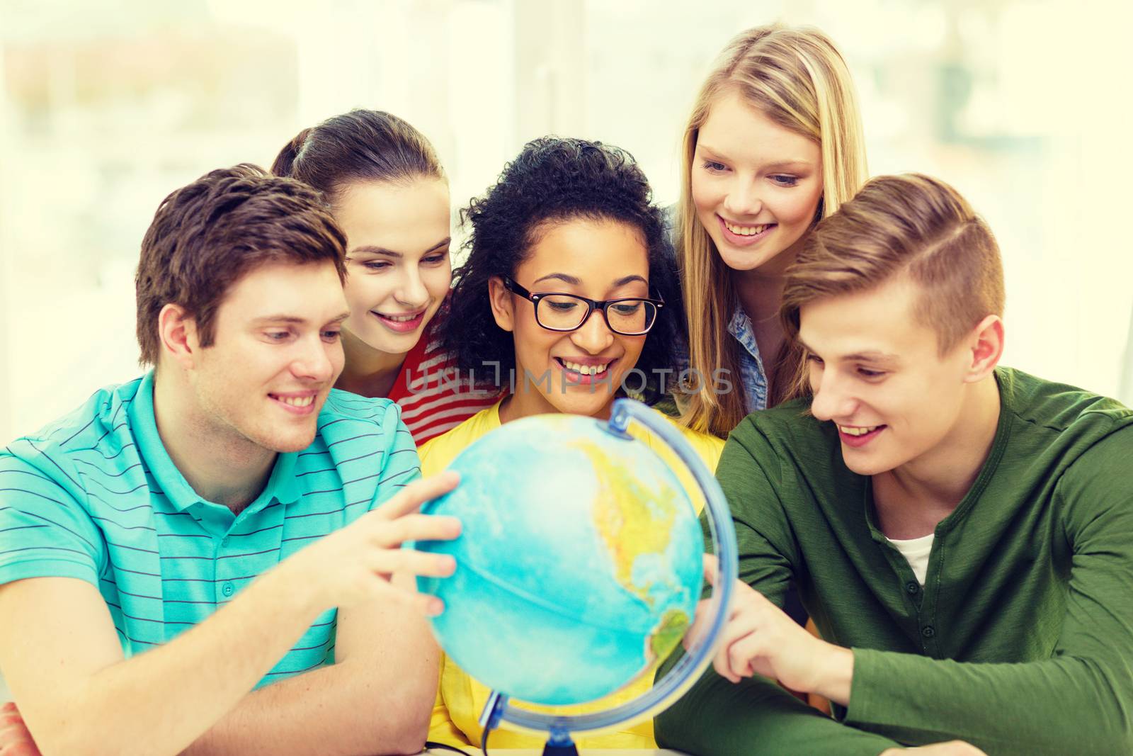 five smiling student looking at globe at school by dolgachov