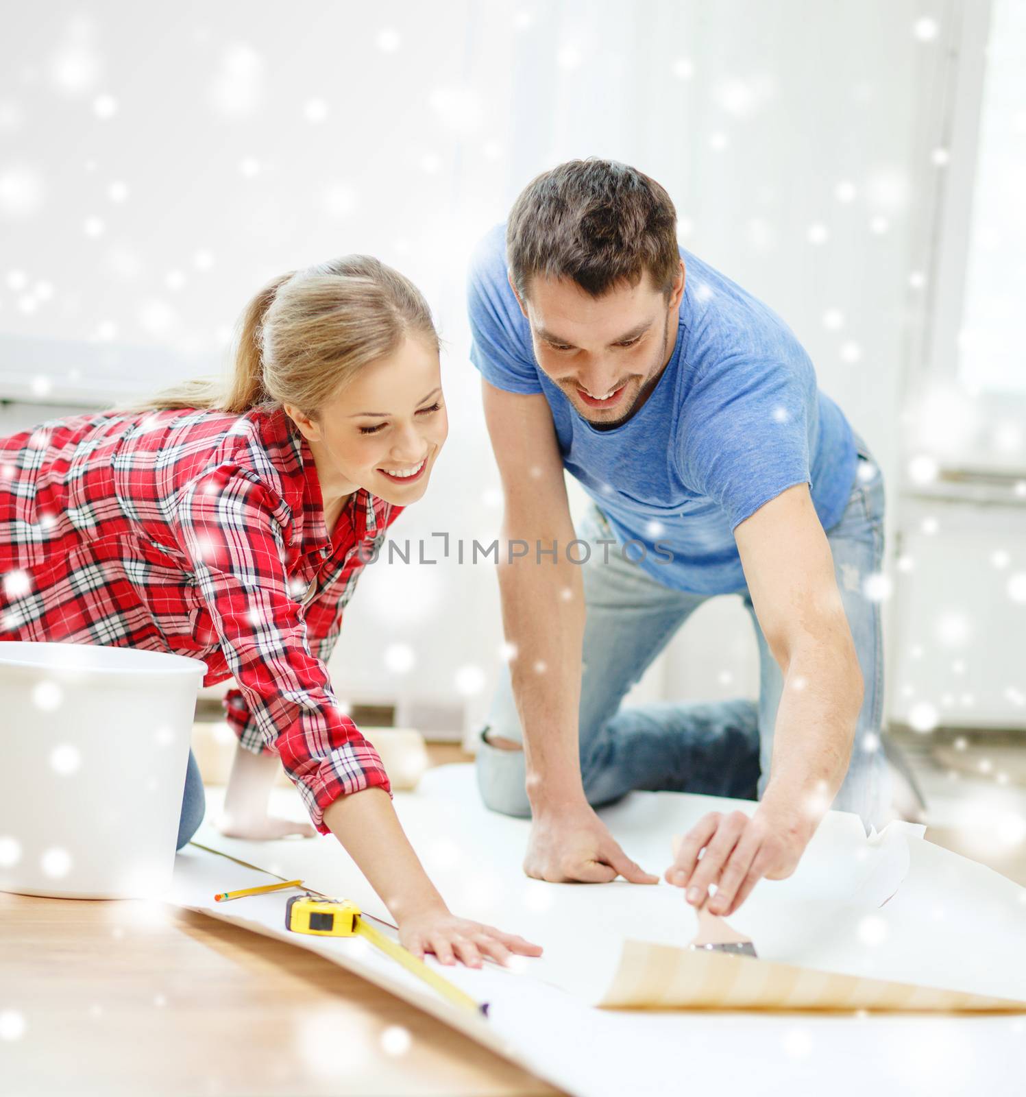 repair, building, teamwork and home concept - smiling couple smearing wallpaper with glue