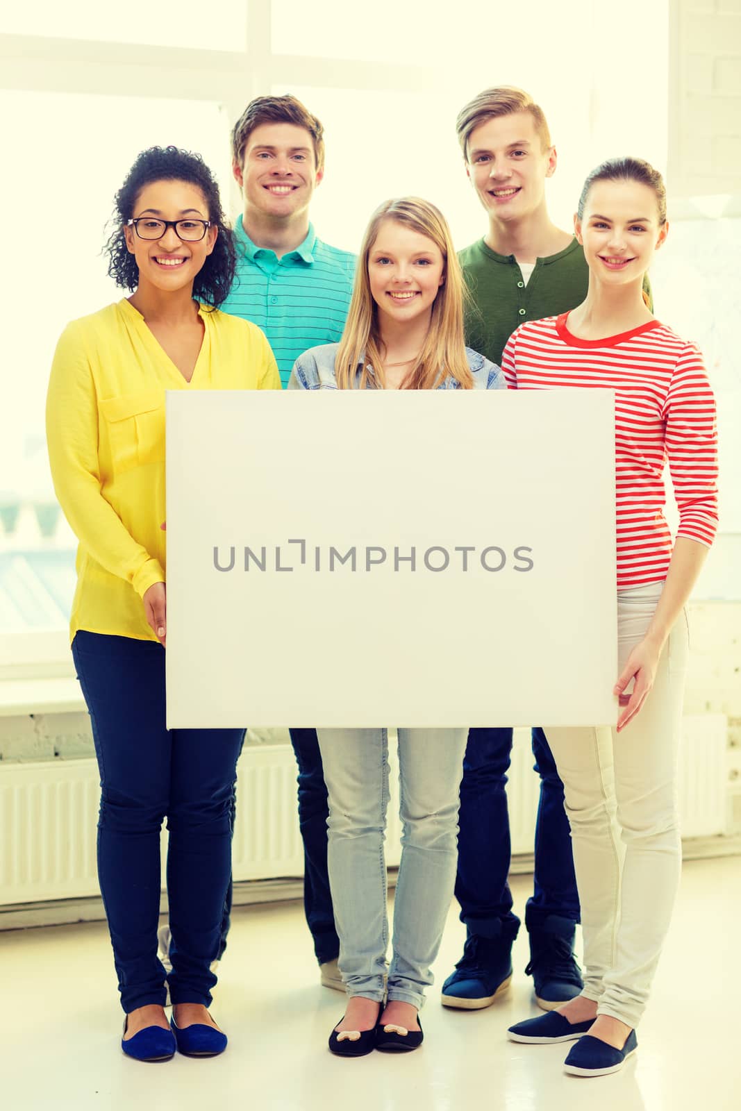 smiling students with white blank board at school by dolgachov