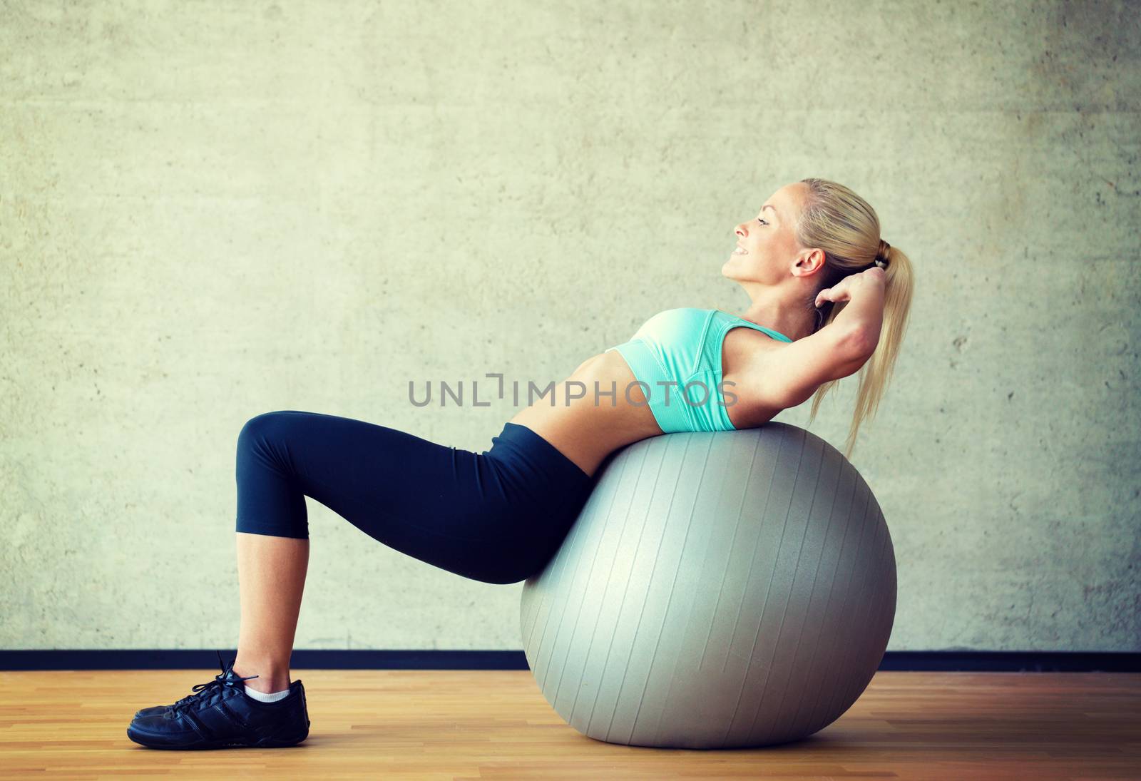 smiling woman with exercise ball in gym by dolgachov