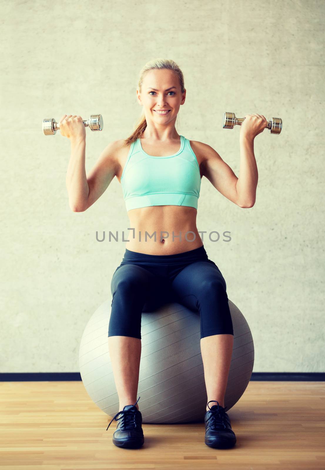 smiling woman with dumbbells and exercise ball by dolgachov