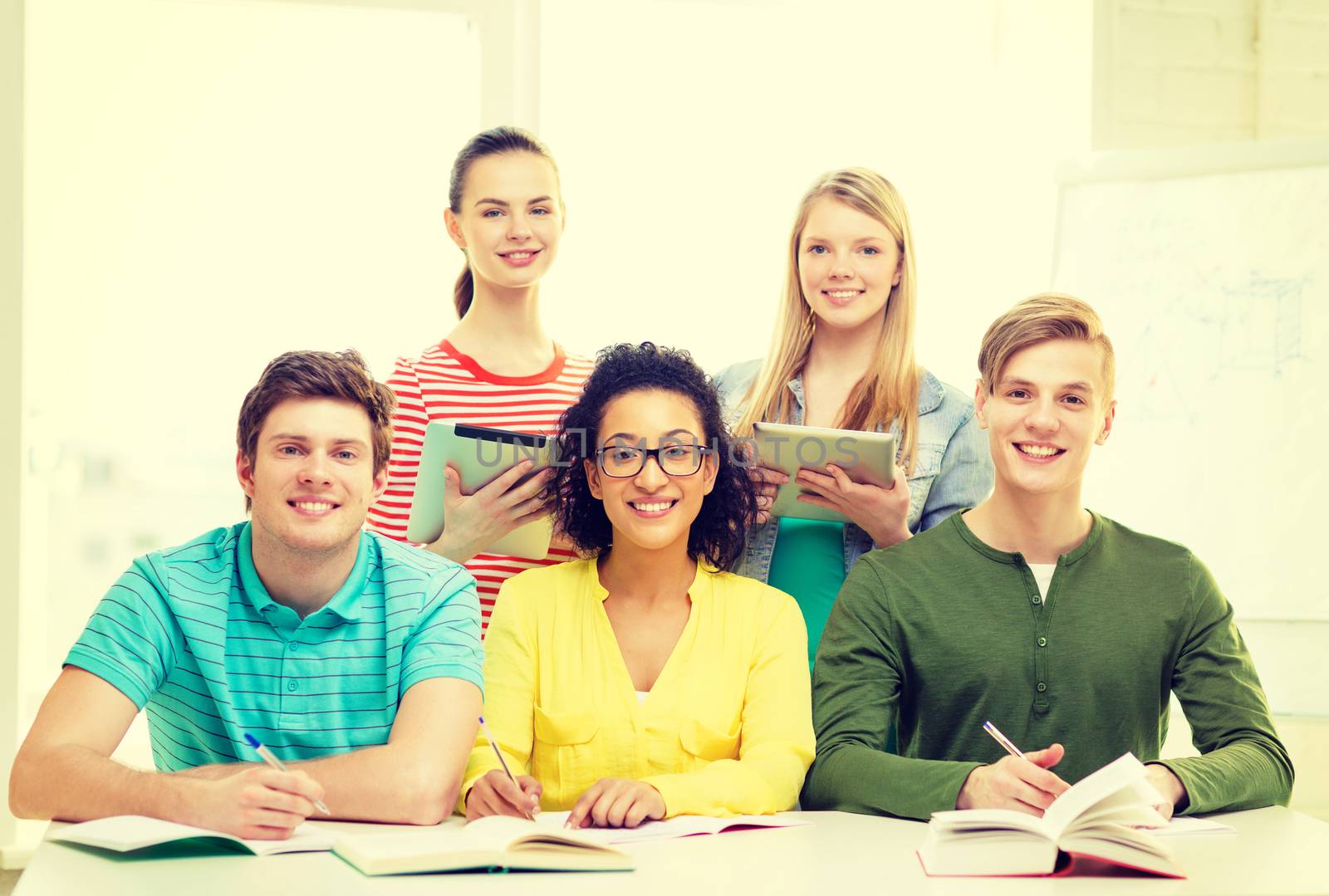 education, technology and school concept - five smiling students with textbooks, tablet pc computers and books at school