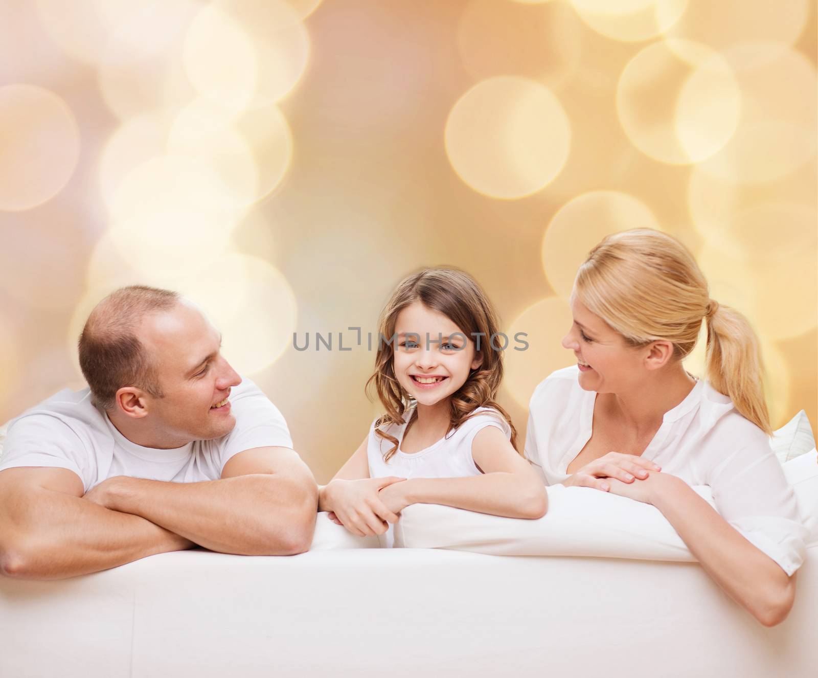 family, childhood, holidays and people - smiling mother, father and little girl over beige lights background