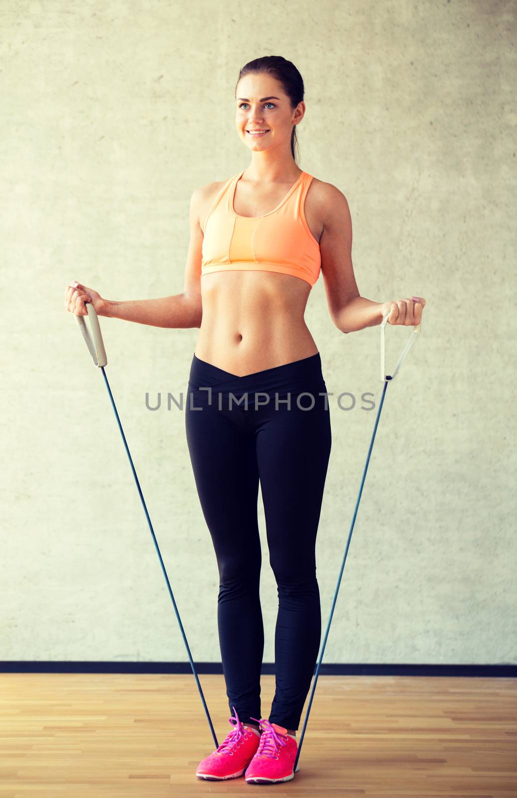 fitness, sport, training and lifestyle concept - smiling woman doing exercises with expander in gym