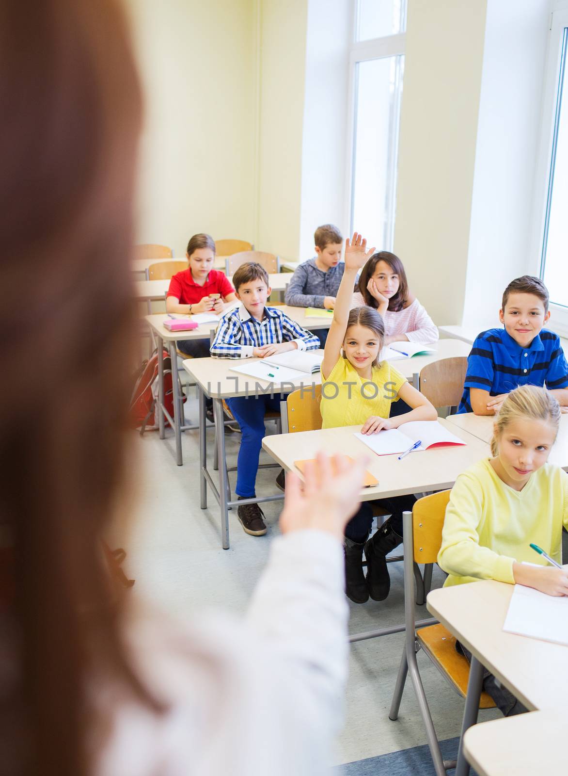 group of school kids raising hands in classroom by dolgachov