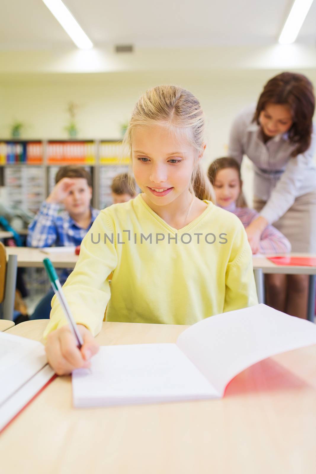 group of school kids writing test in classroom by dolgachov