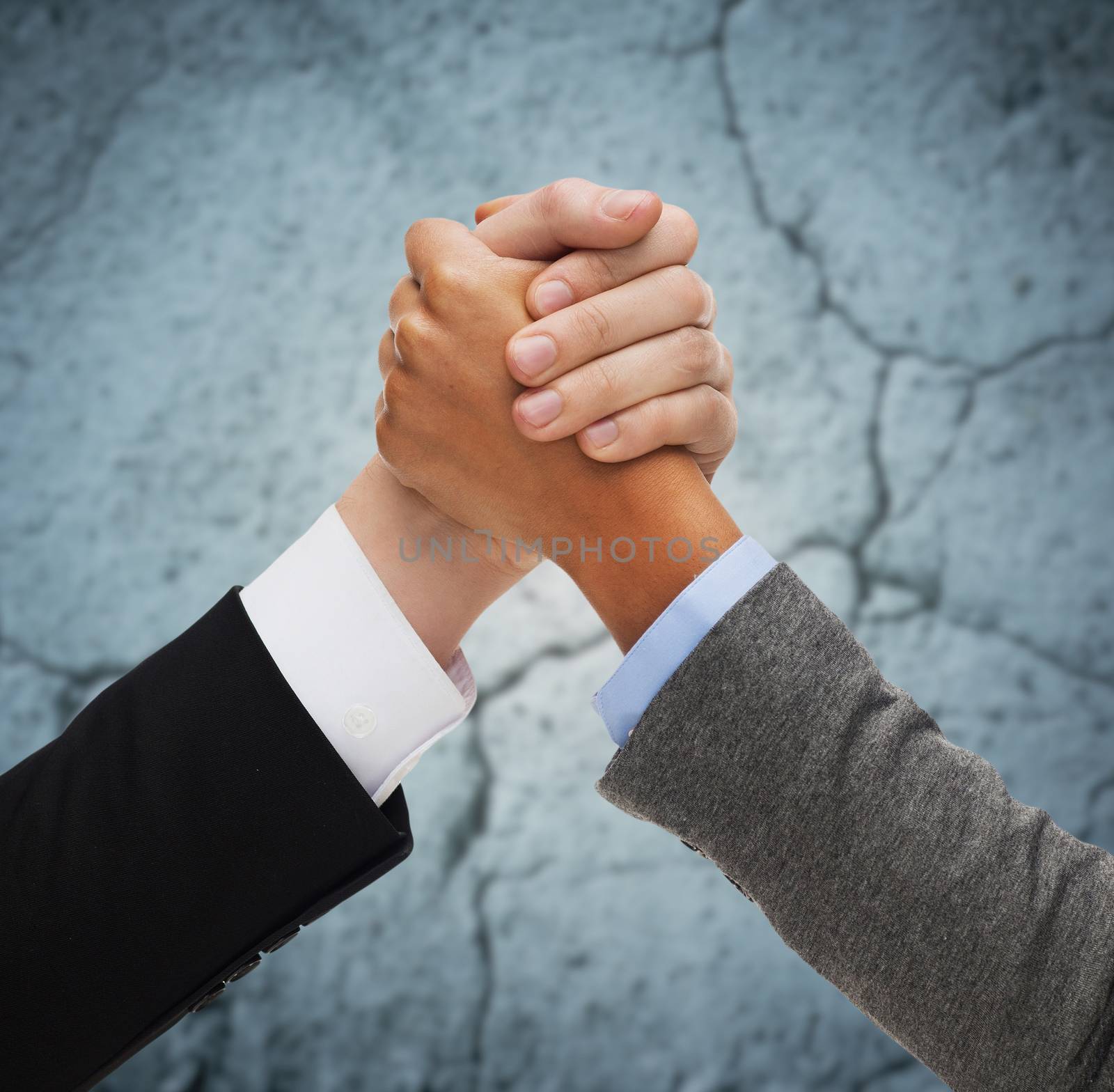 business, people and competition concept - close up of two people hands armwrestling over concrete wall background