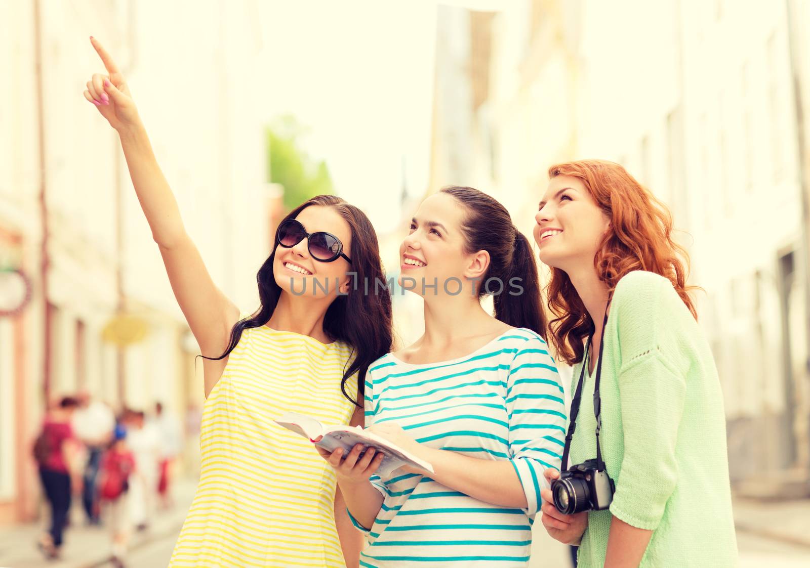 smiling teenage girls with city guide and camera by dolgachov