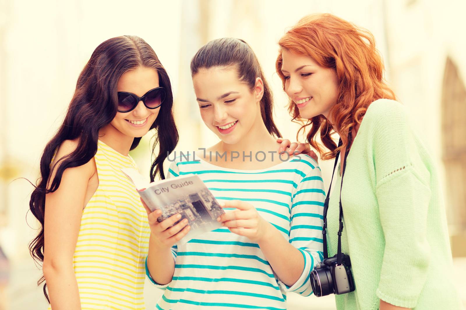 smiling teenage girls with city guide and camera by dolgachov