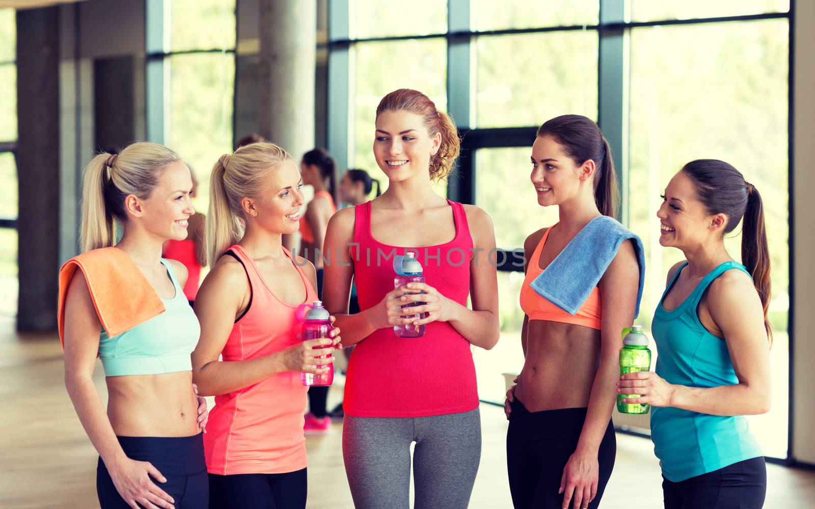 women with bottles of water in gym by dolgachov