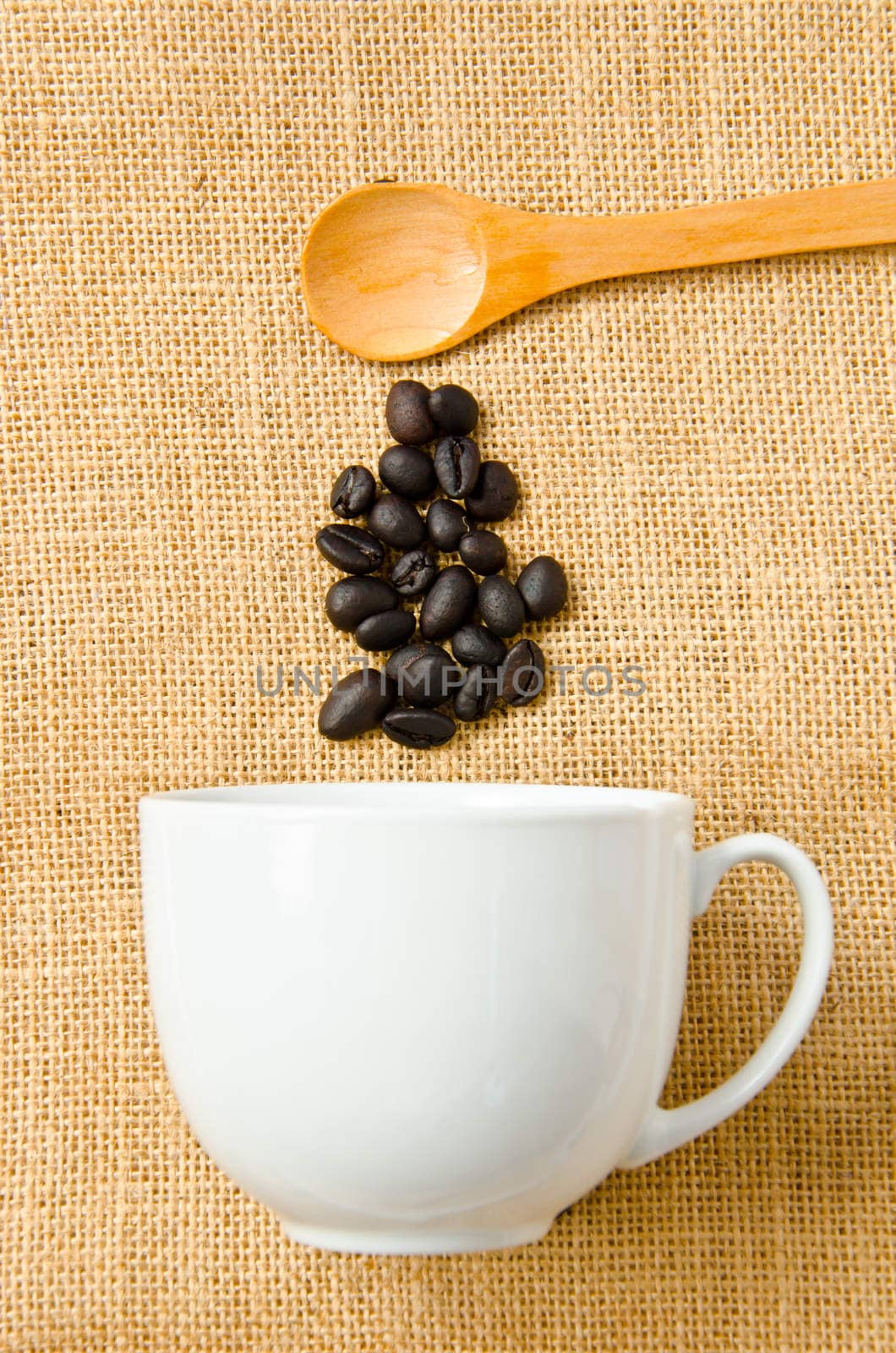Seed coffee, wooden spoon and a cup of coffee on sacks background