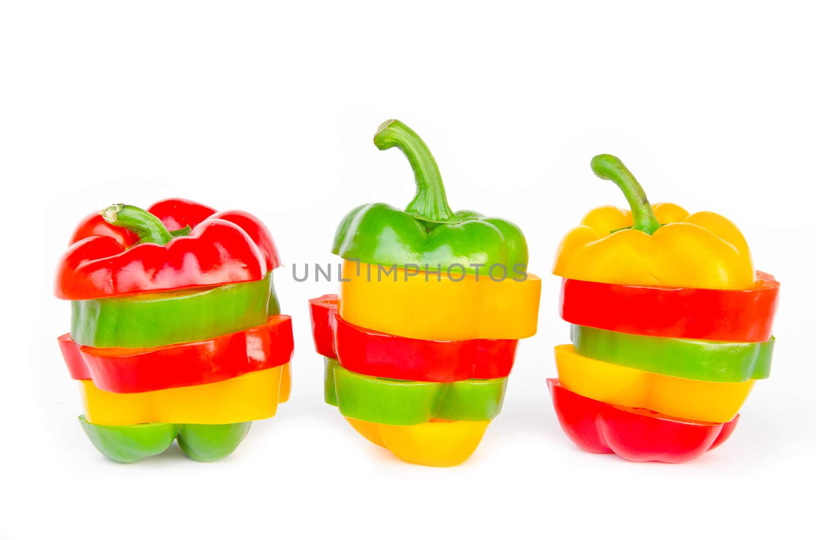 A selection of colorful bell peppers sliced in pieces to make one pepper on white background