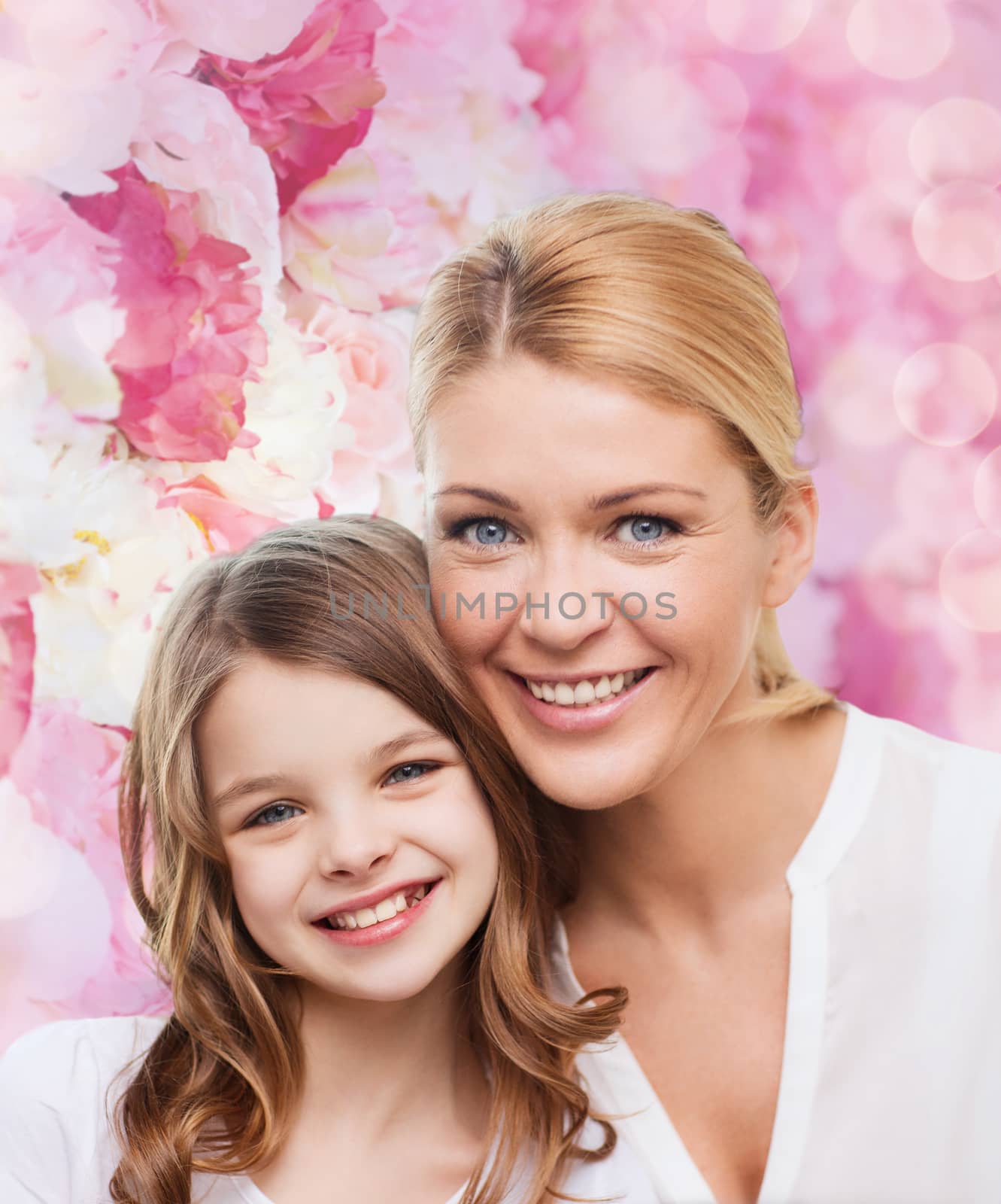 family, childhood, happiness and people - smiling mother and little girl over pink lights background