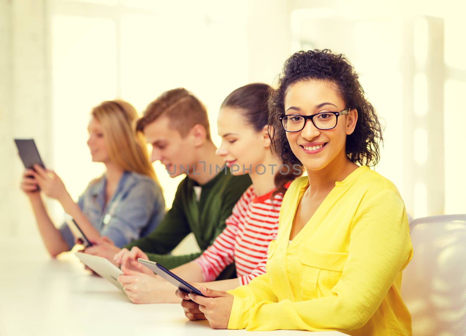 education, technology and internet concept - smiling female students with tablet pc computer and friends on the back at school