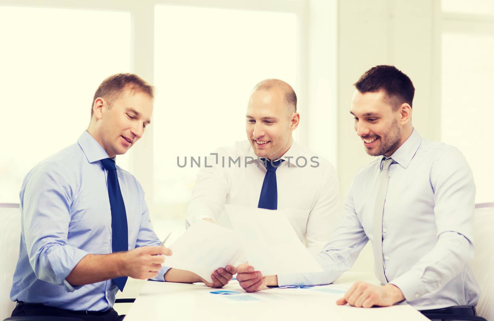smiling businessmen with papers in office by dolgachov